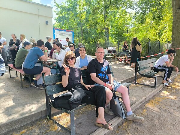 Schnitzeljagd, Tombola und Volleyball-Turnier Momentaufnahme von Schülerinnen und Schülern sowie Lehrkräften der Euro Akademie Berlin. Eine Lehrerin zeigt lächelnd ein Peace-Zeichen in die Kamera.