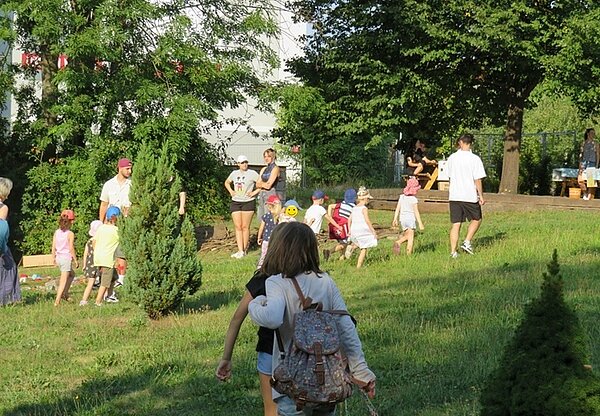 Kinder werden von den Auszubildenden zu Erzieher*innen zum Sinnespfad im großen Garten begleitet.