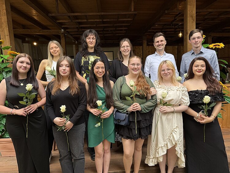 Erfolgreiche Graduation-Feier der Euro Akademie Bamberg/Nürnberg 2025 In festlicher Kleidung haben sich die Absolvent*innen für ein Gruppenfoto aufgestellt. In den Händen halten sie alle eine langstielige weiße Rose.