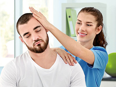 Eine Physiotherapeutin behandelt einen Patienten professionell am Hals und Kopf.