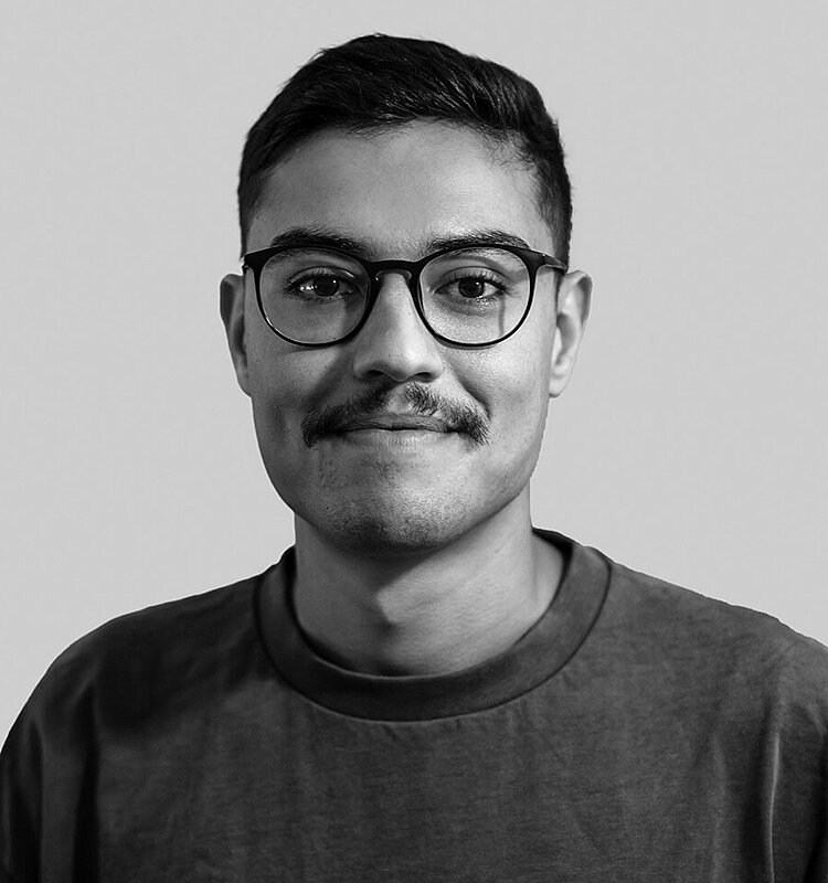 Schwarz-weiß Bild des lächelnden Absolventen Samir Derbali, der eine Brille und einen Oberlippenbart trägt.