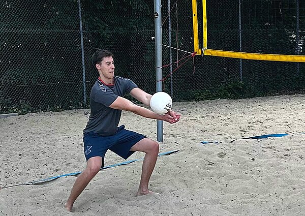 Beachvolleyball mitten in Hannover Ein Schüler der Euro Akademie Hannover steht auf einem Beachvolleyballfeld und ist in der Annahmeposition. Er spielt gerade einen Ball mit beiden Armen, der Blick ist fokussiert.