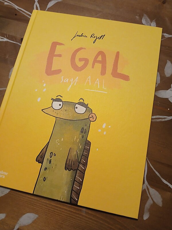 Die Leipziger Buchmesse – ein Erfahrungsbericht Ein gelbes Kinderbuch mit einem lustig illustrierten Aal und dem Titel "Egal sagt Aal"