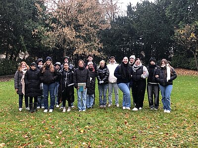 Die Schülerinnen und Schüler posieren auf einer Wiese mit Bäumen für ein Gruppenbild.