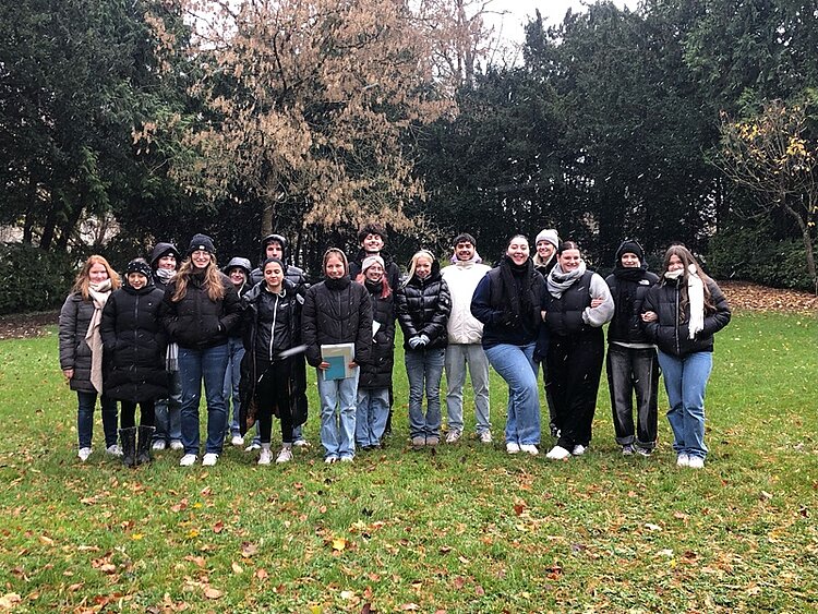 Botanische Exkursion Die Schülerinnen und Schüler posieren auf einer Wiese mit Bäumen für ein Gruppenbild.