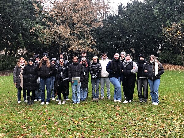 Botanische Exkursion Die Schülerinnen und Schüler posieren auf einer Wiese mit Bäumen für ein Gruppenbild.