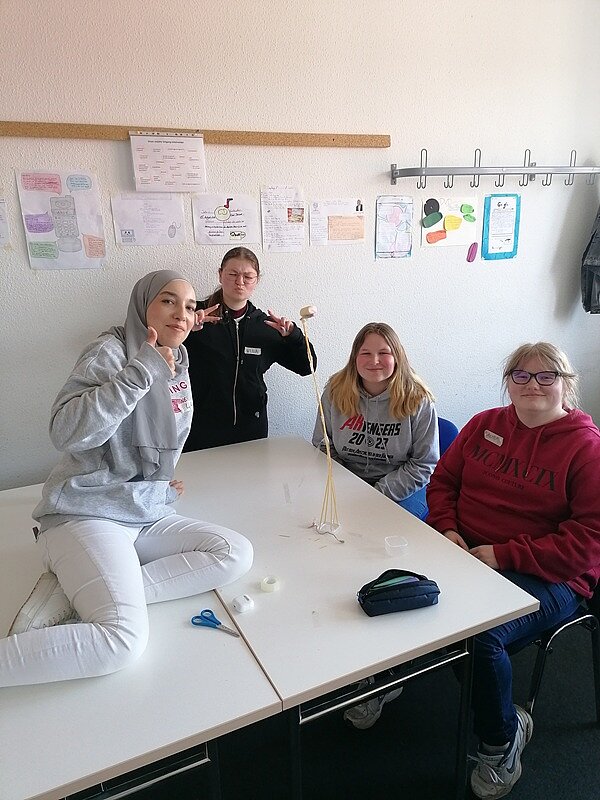 Teamwork Vier Schülerinnen der Euro Akademie Zwickau posieren gut gelaunt für ein Gruppenbild. Eine Schülerin sitzt dabei auf dem Tisch und trägt ein Kopftuch.