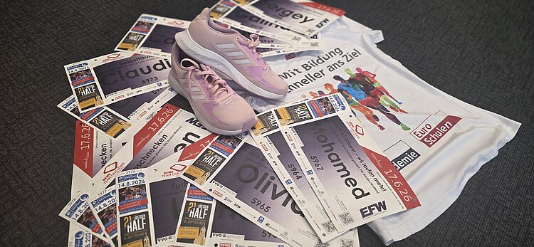 Laufunterlagen mit Startnummern, pinke Sportschuhe und ein Euro-Schulen-Laufshirt liegen auf dem Boden und bereiten auf eine Sportveranstaltung vor.