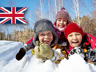 Drei Kinder spielen im Schnee, mit Winterkleidung und UK-Flagge im Hintergrund. 