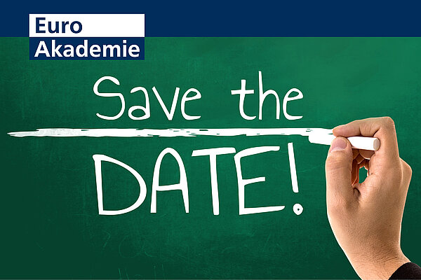 Die Aufschrift "Save the Date!" ist wie mit weißer Kreide geschrieben auf einer grünen Tafel zu sehen, während eine Hand mit Kreide eine Linie zwischen den Wörtern "Save the" und "Date!" zieht. Links oben befindet sich das Logo der Euro Akademie.