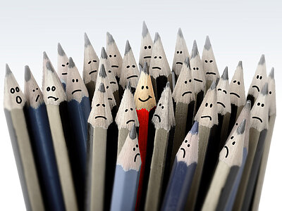 Eine Gruppe von Bleistiften, die alle traurige Gesichter haben, außer einem Bleistift in der Mitte, der ein lächelndes Gesicht hat. Der lächelnde Bleistift ist rot und steht im Vordergrund, während die anderen Bleistifte in verschiedenen Grau- und Blautönen gehalten sind.
