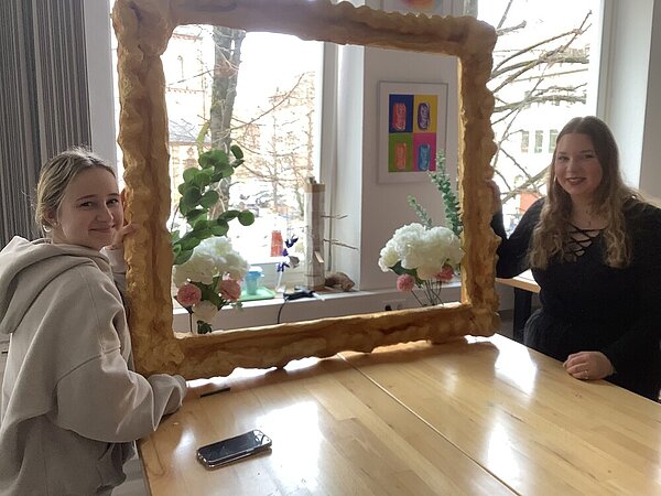 Zwei Schülerinnen präsentieren voller Stolz den fertigen Bilderrahmen.