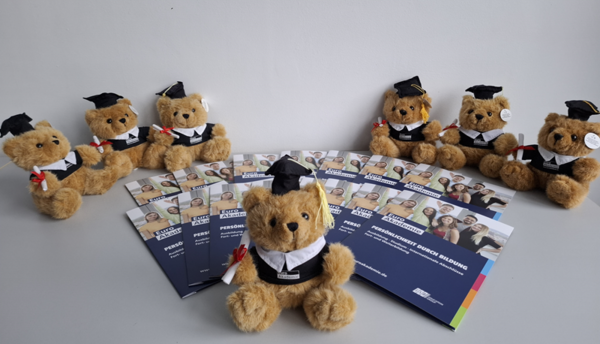 Wir sind Fremdsprachenkorrespondent*innen! Infomaterial und Broschüren der Euro Akademie liegen zentral, drum herum kleine Teddybären in Euro Akademie-Outfit und Absolventen-Hütchen.
