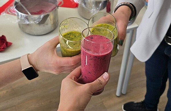 Kennenlerntag Drei Hände von Besuchern des Kennenlerntages prosten sich mit selbst gemachten und gesunden Smoothies zu.