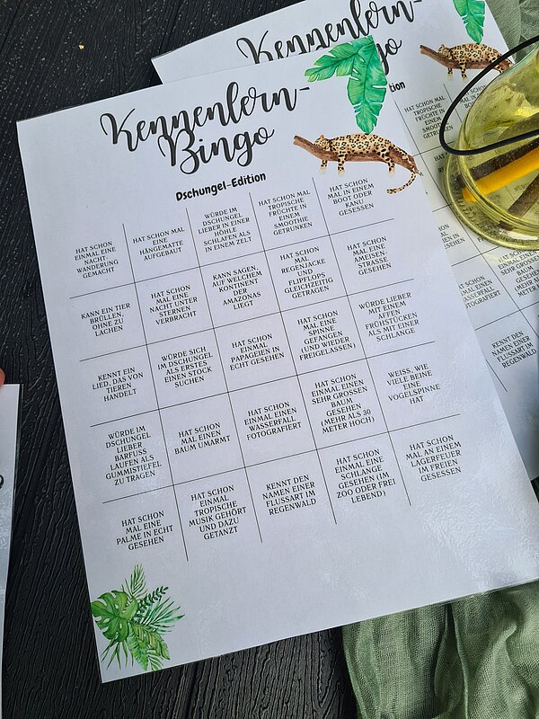 Kennenlerntag der Euro Akademie Rochlitz Ein bedrucktes Bingo-Spielblatt mit dem Titel „Kennenlern-Bingo – Dschungel-Edition“, dekoriert mit Blättern und einem Leoparden.