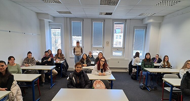 Über 50 neue Azubis gestartet Die neuen Auszubildenden zu Erzieherinnen und Erziehern sitzen im Klassenraum an Tischen und posieren für ein Gruppenfoto.