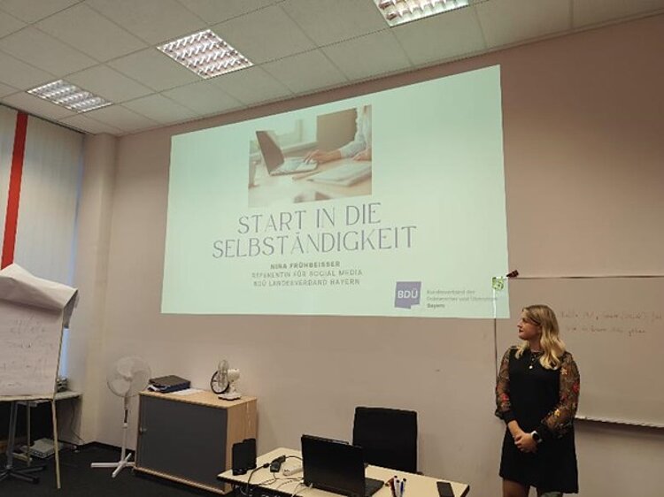 Referentin des BDÜ steht im Klassenraum und hält einen Vortrag mithilfe einer Präsentation über den Beamer.