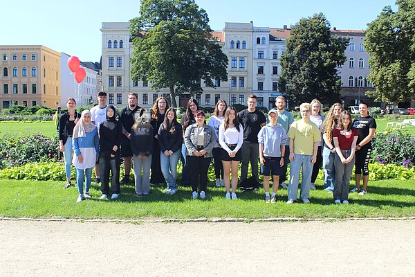 Herzlich Willkommen zum ersten Schuljahr an der Euro Akademie Görlitz! Auf einer sonnigen Wiese inmitten der Stadt haben sich die neuen Auszubildenden für ein Gruppenfoto versammelt. Zwei rote Luftballons haben es auch auf das Bild geschafft. Ein Gesicht wurde nachträglich verpixelt. Auf einer sonnigen Wiese inmitten der Stadt haben sich die neuen Auszubildenden für ein Gruppenfoto versammelt. Zwei rote Luftballons haben es auch auf das Bild geschafft. Ein Gesicht wurde nachträglich verpixelt.