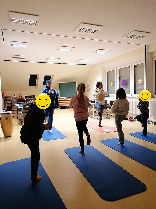 Engagiert und kreativ Zwei Auszubildende machen den Grundschülern auf Yoga-Matten Figuren zum Nachmachen vor.