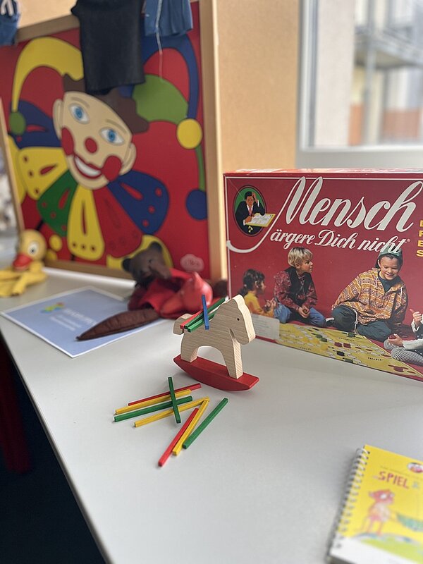 Tag der offenen Tür Auf dem Tisch liegen Spiele, darunter Mensch ärgere Dich nicht.