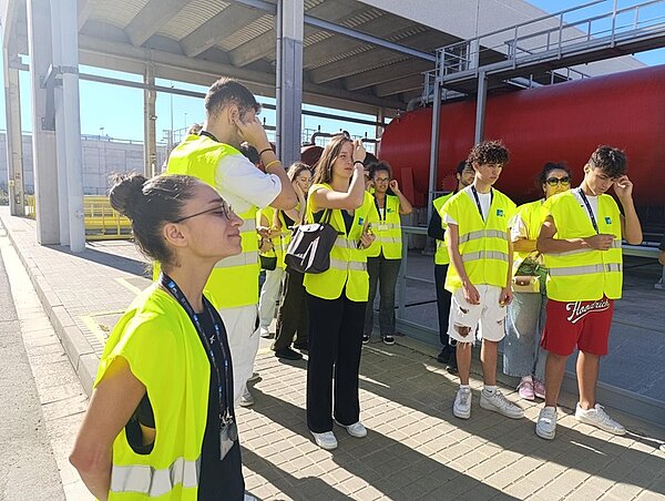 Fotografische Souvenirs vom Erasmus-Austausch in Barcelona Schülerinnen und Schüler in neongelben Westen stehen in einer Fabrikhalle.