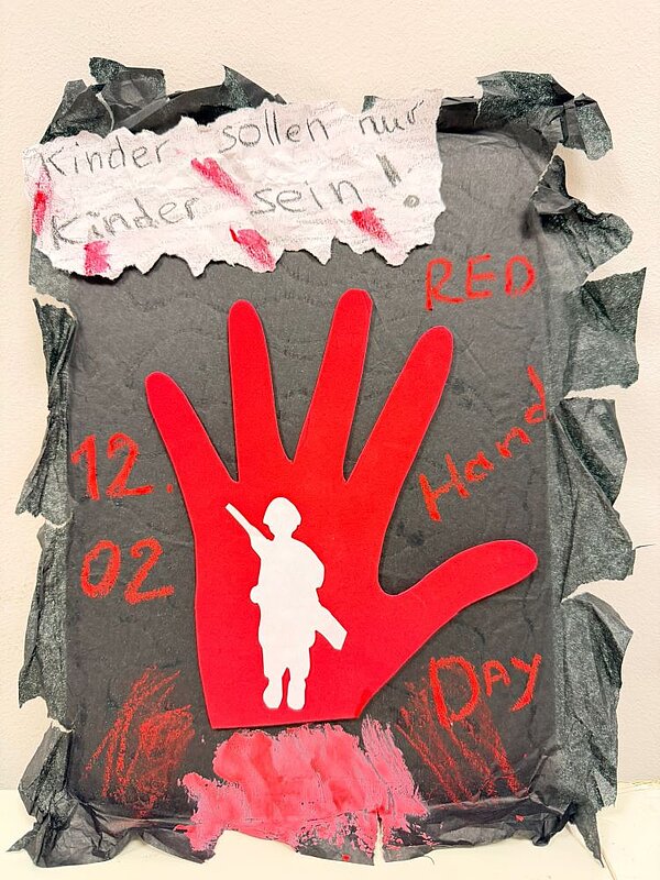 Ein dunkles Plakat mit einem großen roten Handabdruck in der Mitte. Darauf steht ‚12.02‘ und ‚RED Hand Day‘. Im Handabdruck ist die Silhouette eines bewaffneten Soldaten zu sehen. Oben auf dem Plakat steht ‚Kinder sollen nur Kinder sein‘.