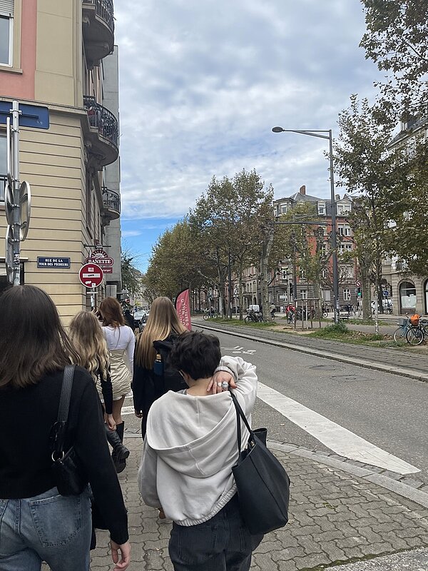 Schülerinnen und Schüler wandern eine Straße entlang.