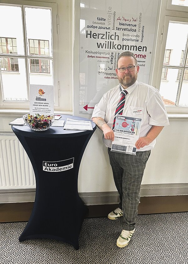 Erfolgreicher Tag der offenen Tür Mitarbeiter der Euro Akademie am Stehtisch empfängt die Besucherinnen und Besucher.