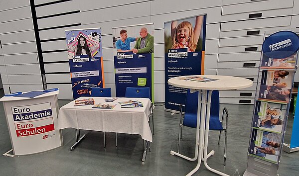 Messestand der Euro Akademie mit Informationsmaterialien, Roll-ups und Stehtischen auf einer Ausbildungsmesse.