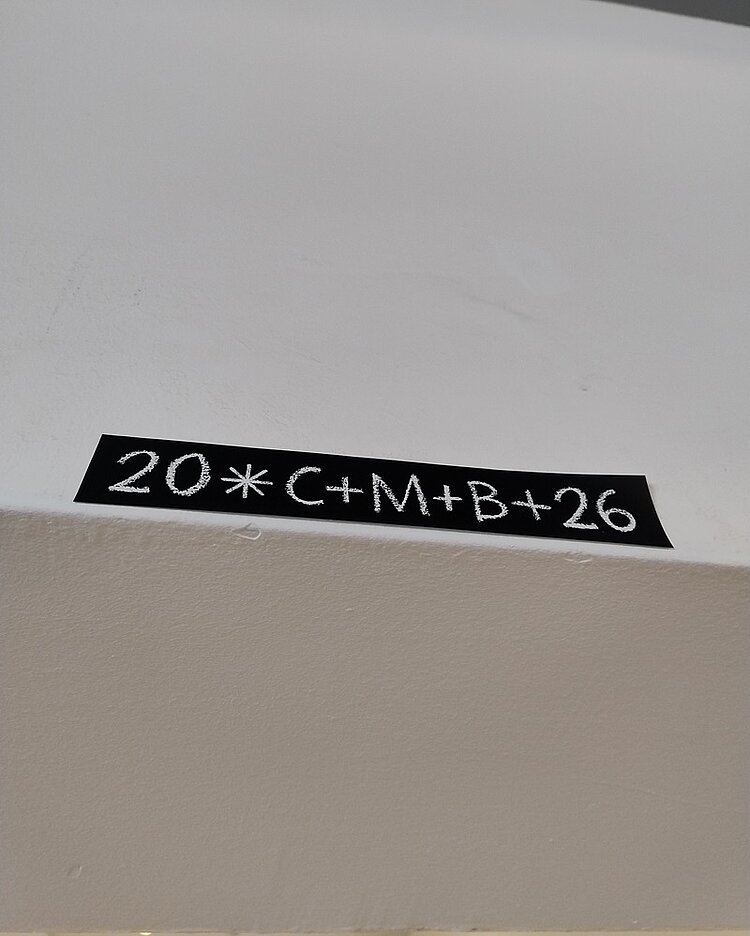 Weiße Wand mit schwarzem Klebestreifen, auf dem in weißer Schrift die traditionelle Sternsinger-Inschrift '20*C+M+B+26' steht. Die Aufnahme entstand anlässlich des Besuchs der Sternensinger am 6. Januar 2026 an den Euro-Schulen und der Euro Akademie Berlin. Die Inschrift symbolisiert den Segen der Sternsinger für das Jahr 2026 und ist gut lesbar mittig auf dem Klebestreifen platziert. Der Hintergrund ist einfarbig und lenkt nicht vom Schriftzug ab.