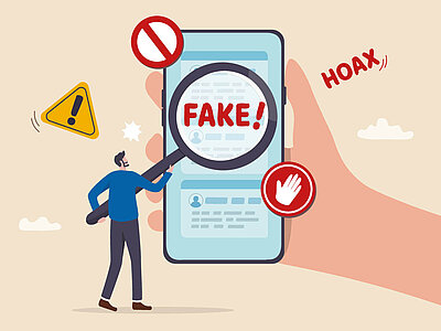 Eine Illustration zeigt eine große Hand, die ein Smartphone hält. Auf dem Smartphone-Bildschirm ist das Wort 'FAKE!' durch eine Lupe vergrößert zu sehen. Um das Smartphone herum befinden sich verschiedene Warnsymbole: ein rotes Verbotsschild, ein gelbes Ausrufezeichen in einem Dreieck und ein rotes Hand-Stopp-Schild. Ein Mann steht neben der Hand und deutet auf das Smartphone. Im Hintergrund ist das Wort 'HOAX' zu sehen.