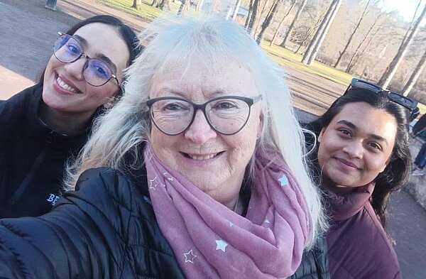 Winter-Sprachferien 2025: „Living in Fairy Tales“ Drei Frauen unterschiedlichen Alters machen ein Selfie und lächeln in die Kamera. Im Hintergrund sind Bäume zu sehen.