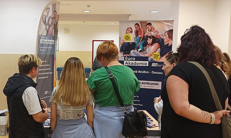 Messebesucherinnen und -besucher stehen am Stand der Euro Akademie Dessau und lassen sich zum Ausbildungsangebot beraten.