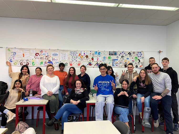 Eingängiges Projekt zum Thema Hygiene Eine Gruppe von Schülerinnen, Schülern und Lehrkräften haben sich vor einem kreativ gestalteten Plakat für ein Foto postiert.