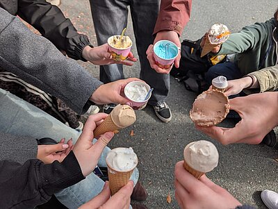 Die Hände mehrerer Menschen halten Eiswaffeln und Eisbecher.