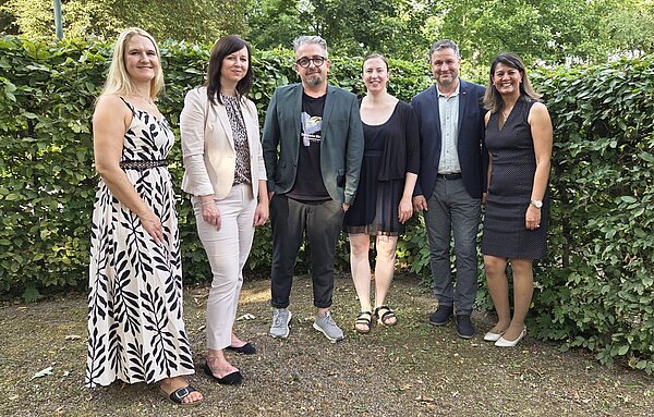 Pflege mit Herz, Verstand und Haltung – Ein bewegender Abschluss an der Euro Akademie Jena Gruppenfoto von sechs lächelnden Personen in festlicher Kleidung, die vor einem grünen Busch stehen. Die Personen sind Teilnehmende an der Abschlussfeier der Pflegefachkraft-Absolvent*innen der Euro Akademie Jena.