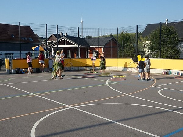 Kinder uns Auszubildende auf dem Sportplatz mit Hula Hoop Reifen.