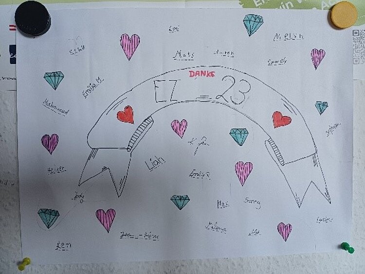Ein ganz besonderer Abschluss Weißes Blatt, auf dem EZ 23 steht und alle Namen der Schülerinnen und Schüler dieser Klasse, inklusive gemalter Herzen und Diamenten.