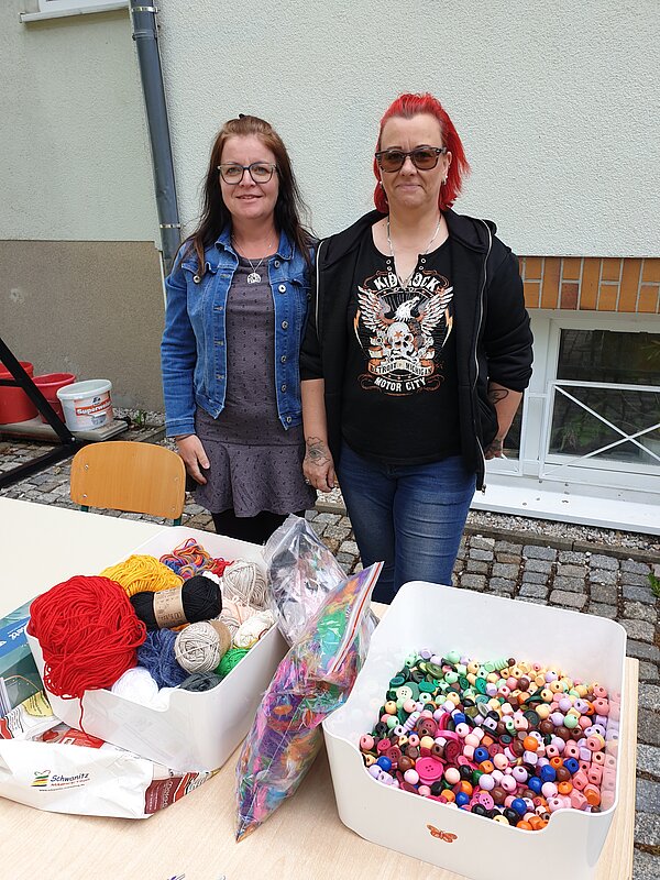 Ein erlebnisreicher Vormittag voller Spiel, Kreativität und Gemeinschaft Zwei Frauen stehen an einem Basteltisch mit bunten Wollknäueln und Perlen, bereit für kreative Aktivitäten.