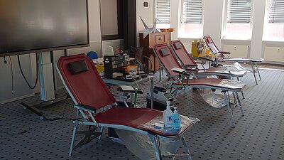 Vier Liegestühle mir brauner Sitzfläche stehen in einem klinischen Raum. Diese noch leeren Stühle sind für Lebensretter*innen reserviert. Startet in den Feierabend mit einer Blutspende und werdet eine*r davon!