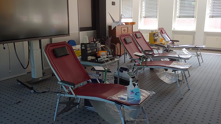 Rückblick auf unsere Blutspenden-Aktion: Nach der Schule Gutes tun Vier Liegestühle mir brauner Sitzfläche stehen in einem klinischen Raum. Diese noch leeren Stühle sind für Lebensretter*innen reserviert. Startet in den Feierabend mit einer Blutspende und werdet eine*r davon!