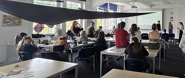 Die Teilnehmenden des Programmes sitzen und stehen im Unterrichtsraum und erarbeiten die Themen UV-Schutz.