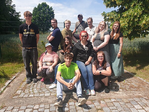 Ein erlebnisreicher Vormittag voller Spiel, Kreativität und Gemeinschaft Eine Gruppe junger Menschen posiert auf einem Gehweg für die Kamera.