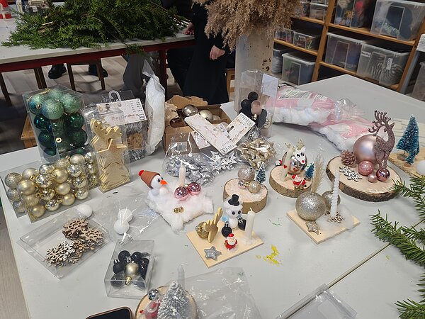 Ein Tisch mit verschiedenen selbstgebastelten Weihnachtsgeschenken aus Weihnachtskugeln, Kerzen und winterlichen Accessoires.