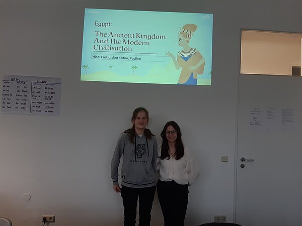 Der nächste Schritt zur Karriere: Career Week Zwei Schülerinnen posieren unter der Projektion einer Präsentation an der Wand, die den Titel "Egypt: The Ancient Kingdom And The Modern Civilisation" hat und von Hind, Emina, Ann Katrin und Paulina ausgearbeitet wurde.