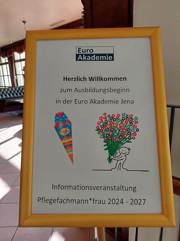 Ausbildungsstart an der Euro Akademie Jena Ein Bild von einer Tafel, die vor einem Klassenraum steht, auf der eine Schultüte ist und ein Blumenstrauß. Darüber steht ein Willkommenstext.