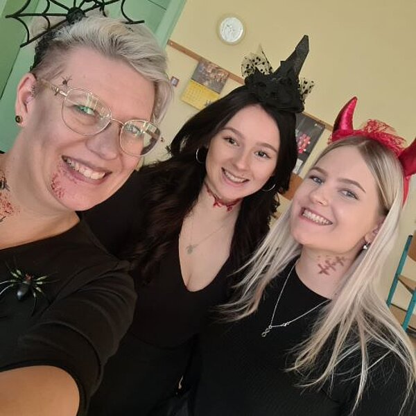 Drei junge Frauen in Halloween-Verkleidung lächeln in die Kamera.