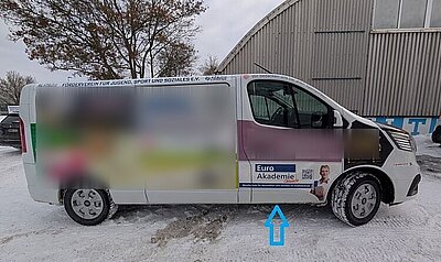 Ein weißer Transporter, der voller Werbeanzeigen ist, unter anderem rechts unten für die Euro Akademie.