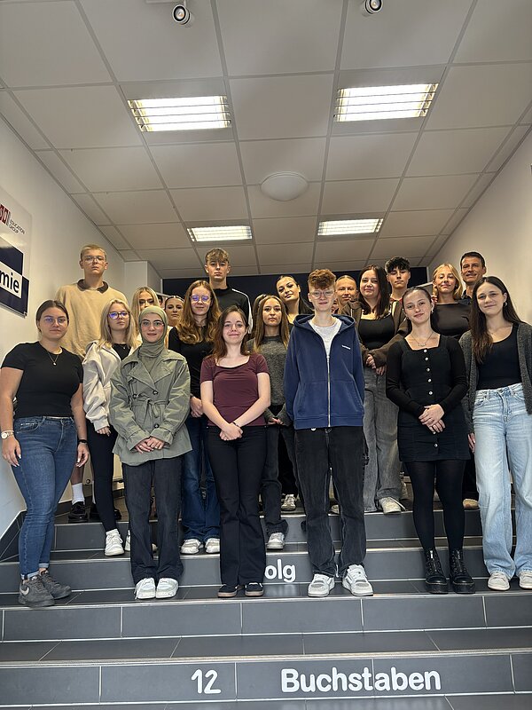Weitere Gruppe von Schülerinnen, Schülern und Mitarbeitenden der Euro Akademie Zwickau steht auf einer Treppe im Schulgebäude für ein gemeinsames Gruppenfoto.