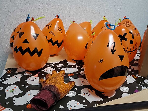 Organgefarbene Luftballons, die als gruselige Kürbisse angemalt sind.